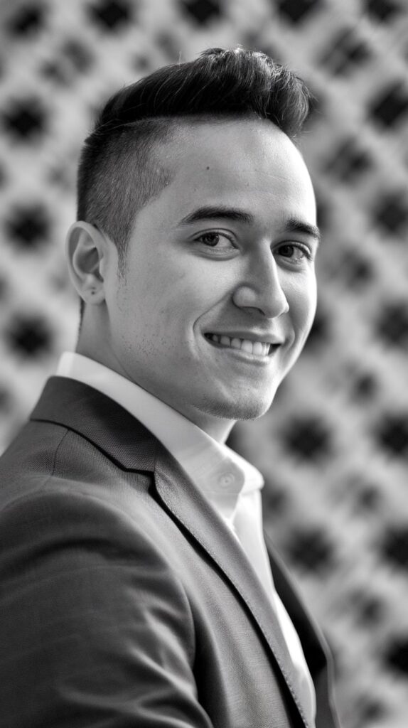 Muchacho sonriendo mucho y mirando fijamente al frente con un traje muy elegante en blanco y negro